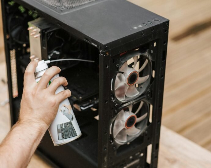 Hand using compressed air to clean the inside of a computer tower during PC maintenance