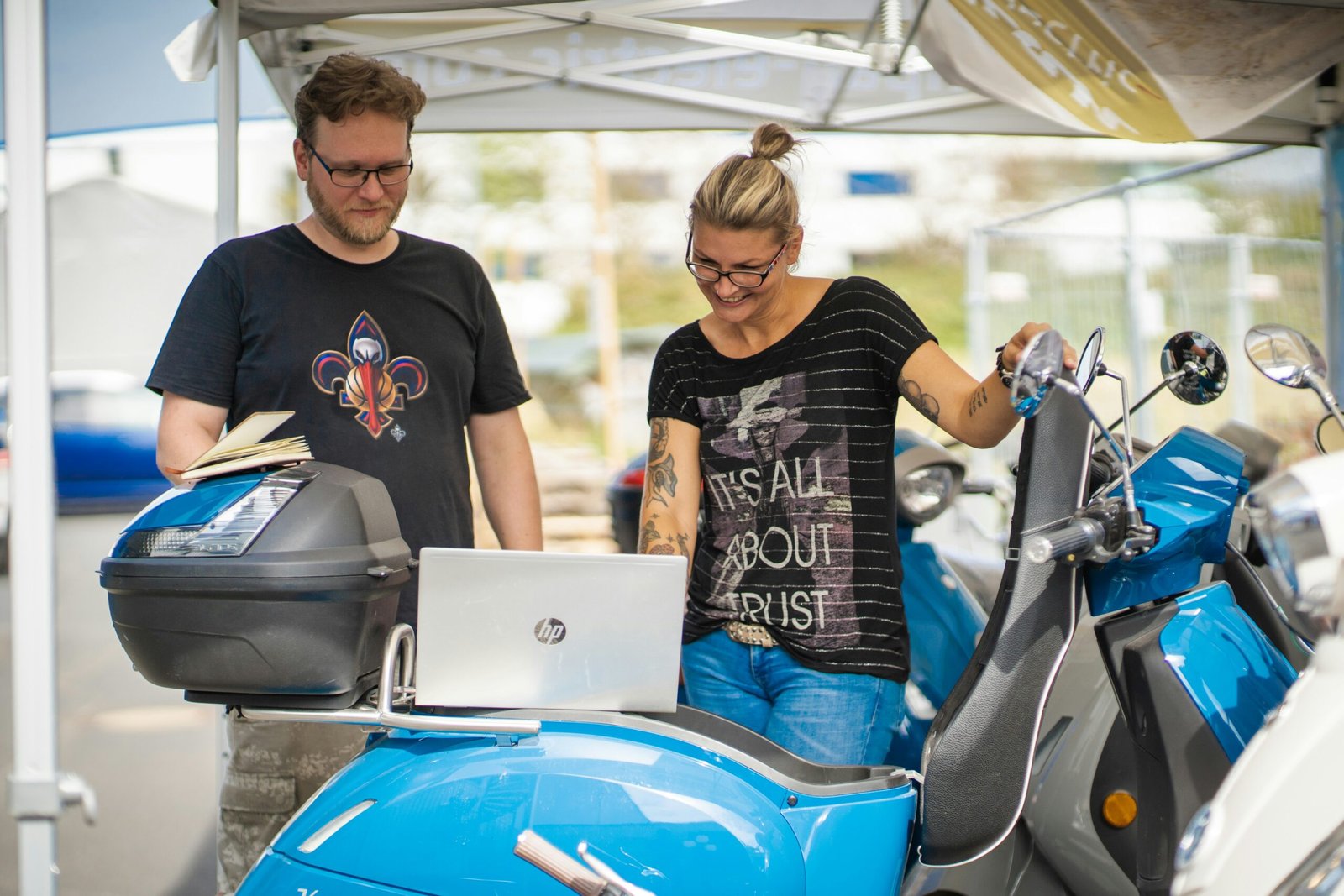 Man and woman troubleshooting laptop on a motorcycle.