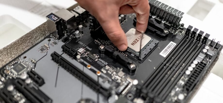 Hand installing or removing a CPU from a motherboard, showing the pins of the CPU.